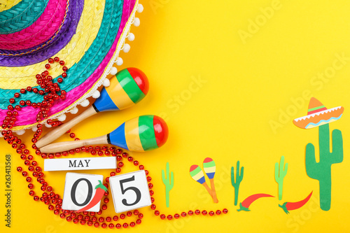 Mexican hat with maracas, cube calendar and paper cactuses on yellow background