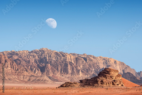 view on Red Sand Dune in incredible lunar landscape in Wadi Rum in the Jordanian desert with huge moon above. Wadi Rum also known as The Valley of the Moon, Jordan - Image