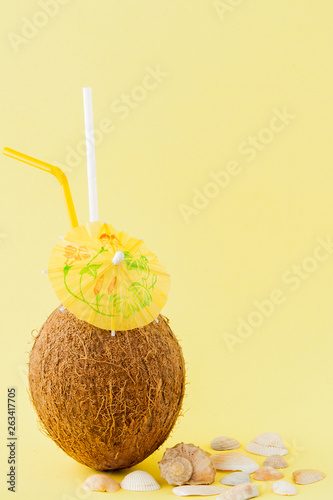 Fresh Coconut cocktail with a straws on yellow background, copy space