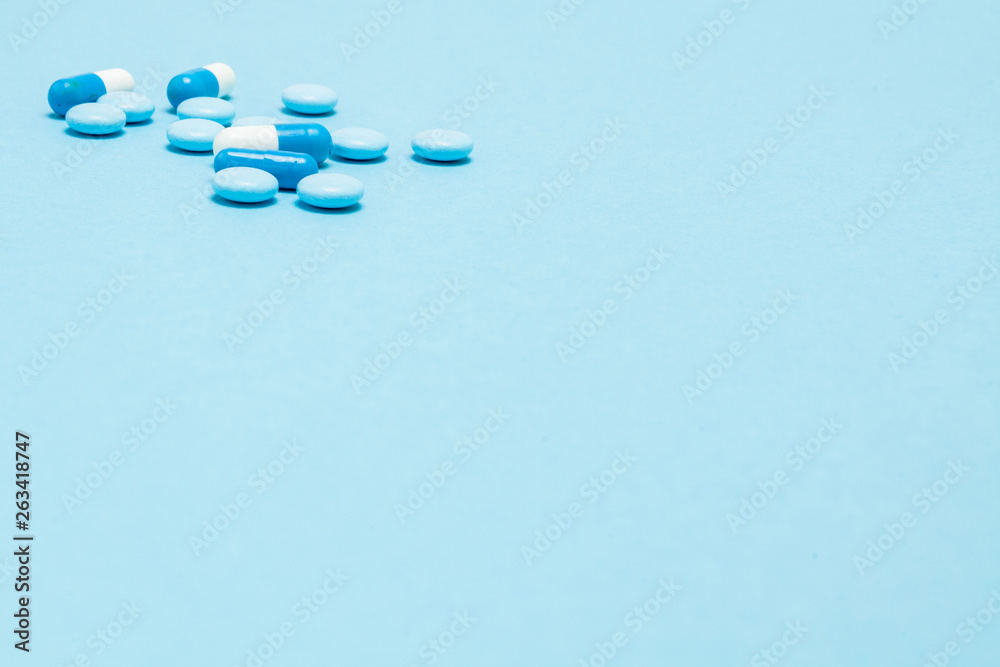 Scattered blue pills on blue table. Mock up for special offers as advertising, web background or other ideas. Medical, pharmacy and healthcare concept. Copy space. Empty place for text or logo