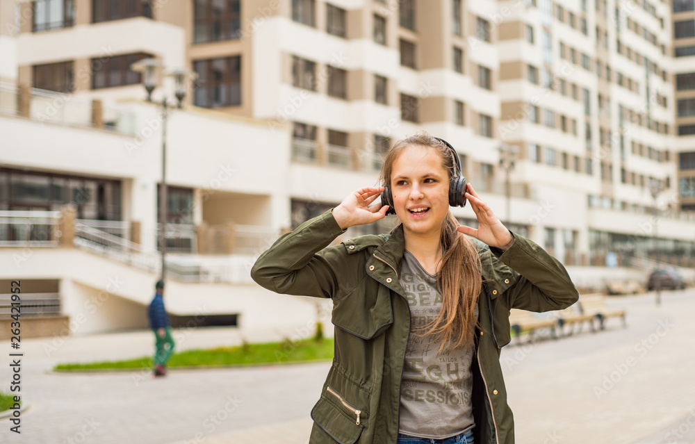 Outdoor portrait of young teenager brunette girl with long hair. young woman listening to music using mobile phone