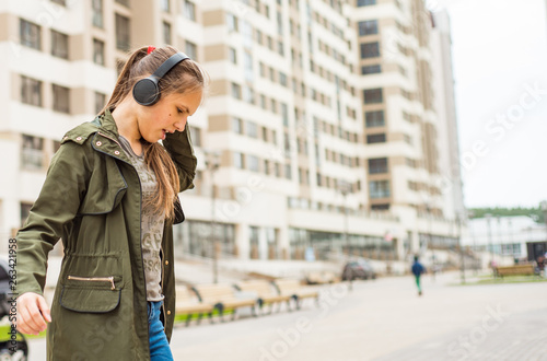 Outdoor portrait of young teenager brunette girl with long hair. young woman listening to music using mobile phone