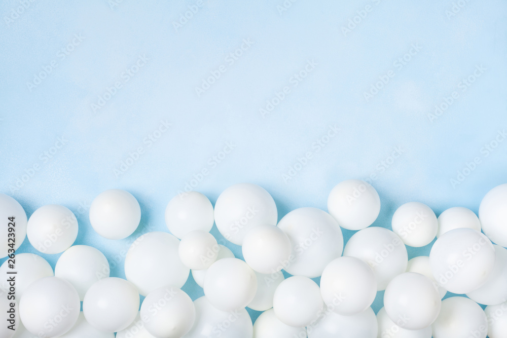 Pastel blue table with white balloons border top view. Party or birthday background. Flat lay style.