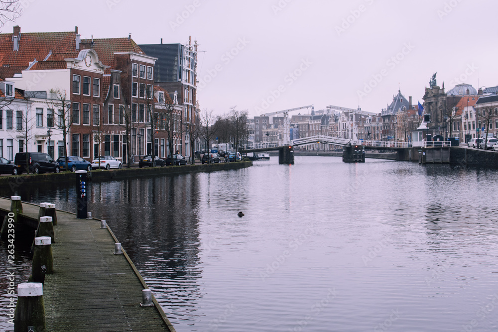 Spectacular cityscape of Haarlem, Netherlands. Wooden path on the left side and the old white drawbridge on the right. Beautiful bricked houses on a background.