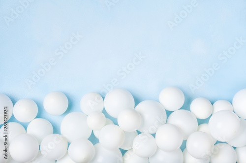 Pastel blue table with white balloons border top view. Party or birthday background. Flat lay style.