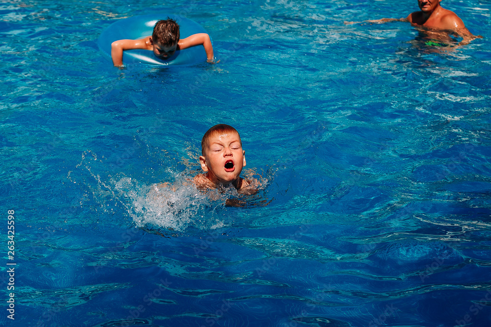 seven-year-old child learns to swim in the outdoor pool