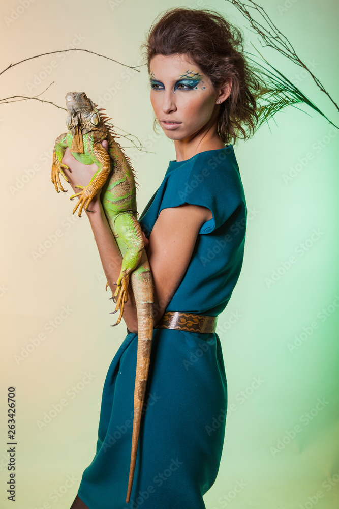 Wild animal in the hands of man. Bold image of a modern woman predator with iguana. Animal out of it. Amazon. Temptress.