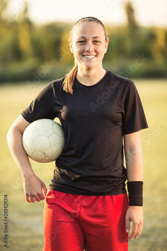 Young female soccer player posing with soccer ball