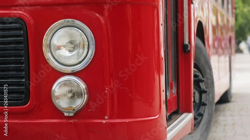 Close-up front side view of the red double-decker bus standing on the street at daytime. photo