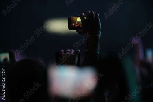 Hand of a fan with a phone filming a concert