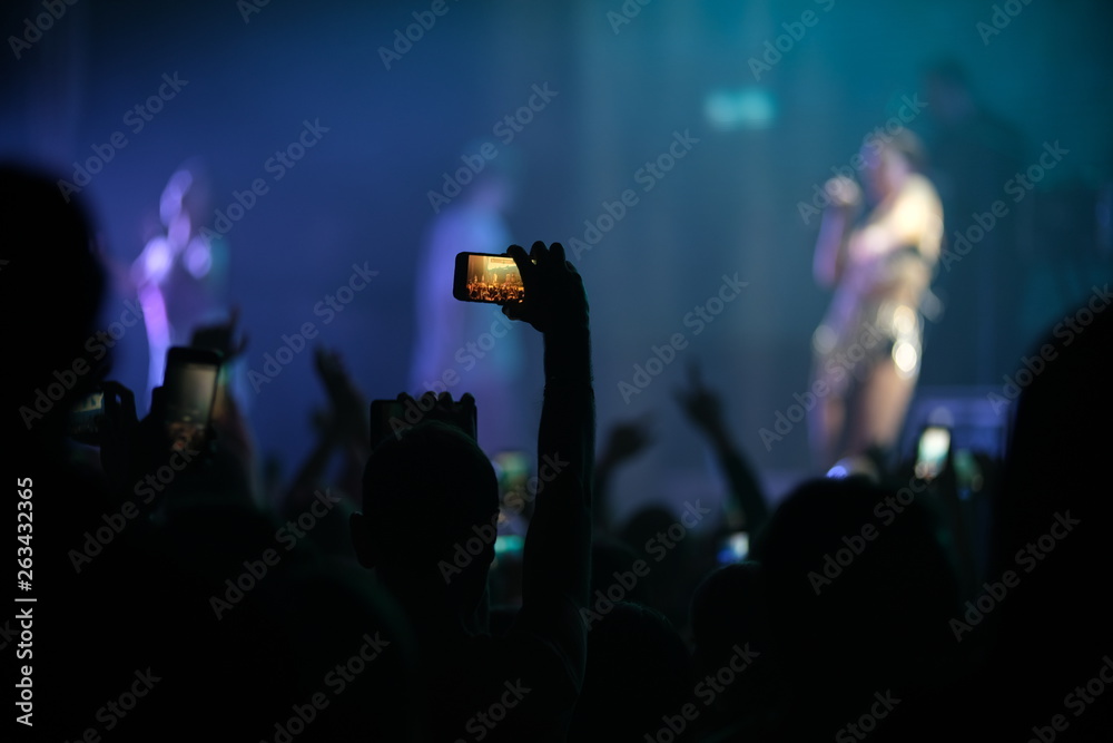 Hand of a fan with a phone filming a concert
