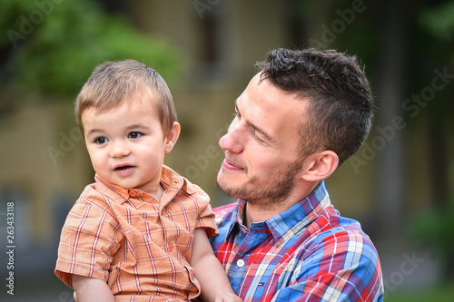 father holds son in a park