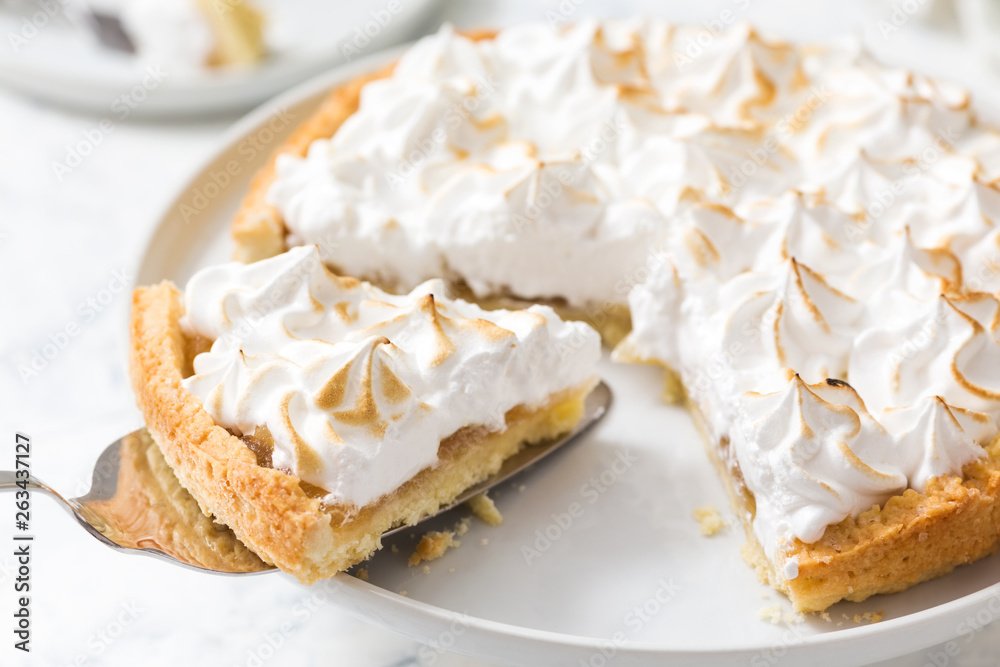 Slice of lemon meringue tart on a white plate Slice of lemon meringue tart on a white plate