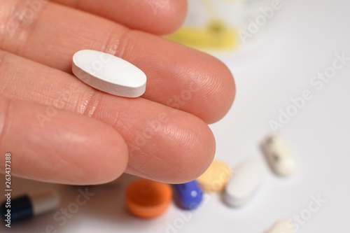 Various medical pills and capsules picked up with hand