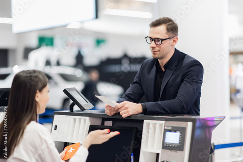 Handsome businessman handing over air ticket at airline check in counter photo