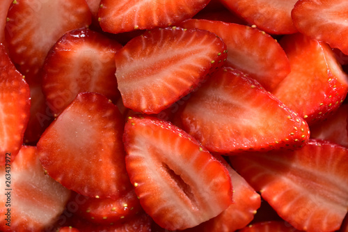Appetizing texture consisting of sliced large summer berries of red strawberry