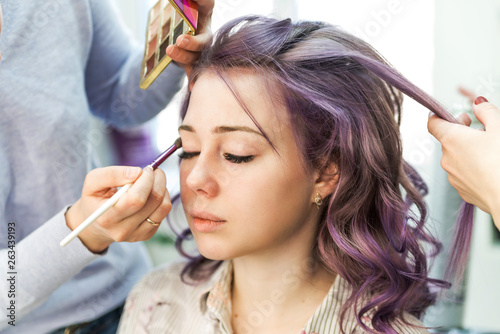 Stylist and makeup artist preparing bride before the wedding in a morning