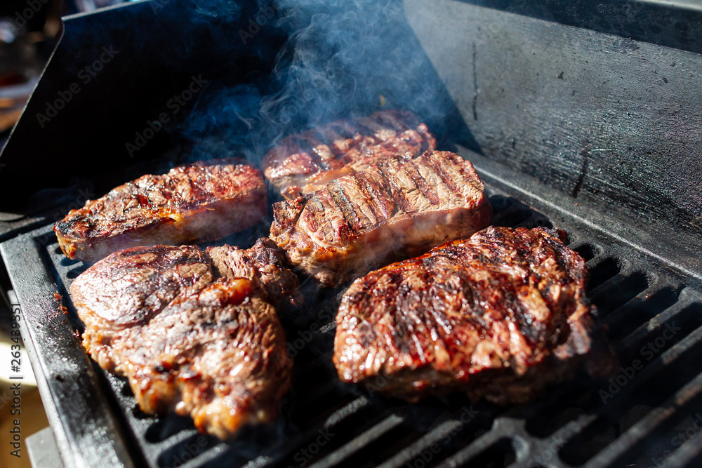 Beef steak cooking. Rib eye steak. Raw meat. Juicy marbled meat on BBQ grill. Medium rare meat roasting Beef steak cooking. Rib eye steak. Raw meat. Juicy marbled meat on BBQ grill. Medium rare meat roasting