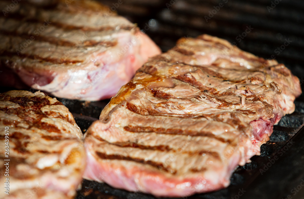 Beef steak cooking. Rib eye steak. Raw meat. Juicy marbled meat on BBQ grill. Medium rare meat roasting
