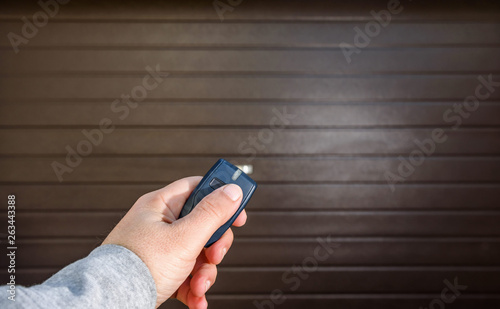 Garage door PVC. Hand uses remote controller for closing and opening garage door