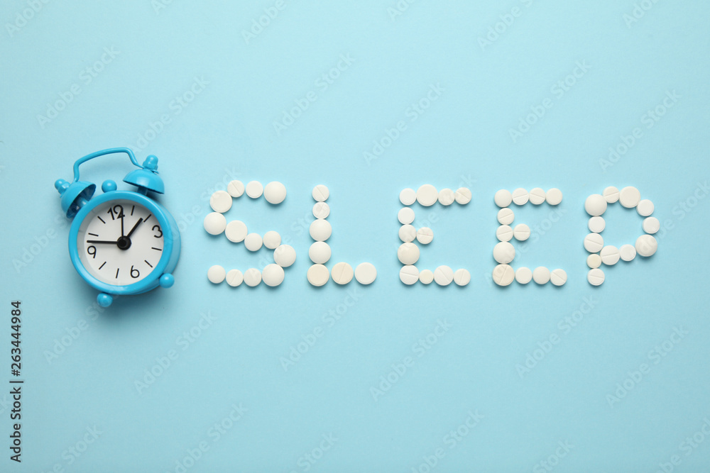 Sleeping pills and an alarm clock, insomnia concept. Nightmares and
