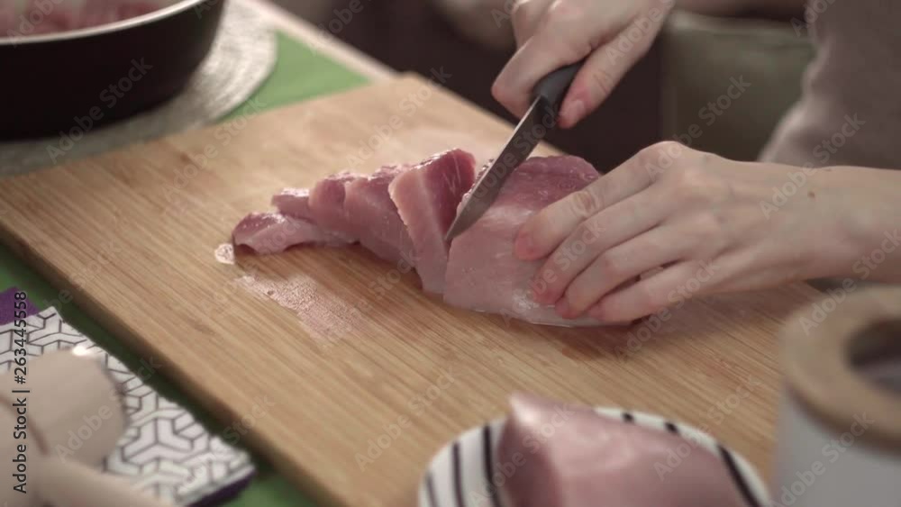 Girl cuts pork meat beef on a wooden Board, close-up, cooking Girl cuts pork meat beef on a wooden Board, close-up, cooking