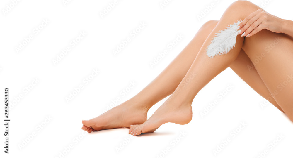woman touching with feather to her shiny smooth skin on legs after hair removed. Hair removal, care about legs - obrazy, fototapety, plakaty 
