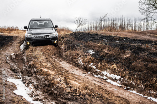 Canvas Print Black crossover on dirt road with deep mud