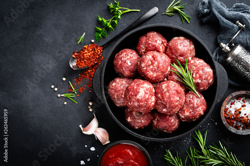 Fresh raw beef meatballs with spices and tomato sauce