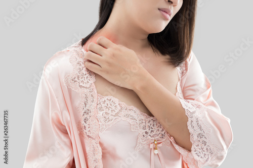 Asian women in the silk nightwear and orange robe are scratching their nape due to itching on a gray background, Female has an itching neck, Healthcare And Medicine, People with skin problem concept.