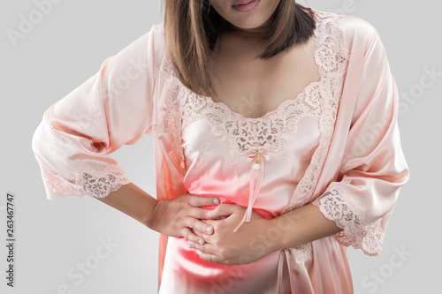 The woman in silk orange nightwear having appendicitis pain at night. Female suffering from stomach ache. inflammatory bowel disease. Irritable Bowel Syndrome. photo