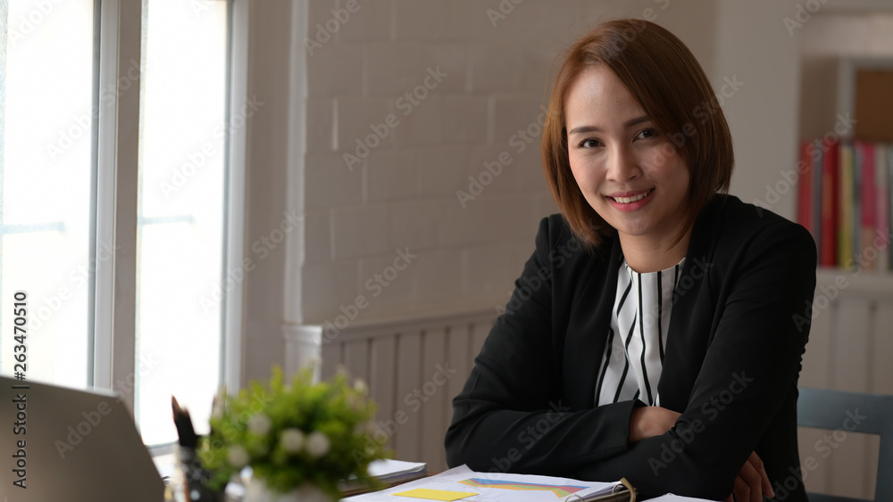 Portrait of confident Asian businesswoman on desk in office Portrait of confident Asian businesswoman on desk in office