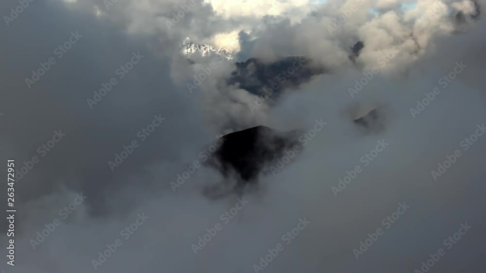 A distant snowcapped Himalayan peak can be seen through clouds rolling into the frame. A distant snowcapped Himalayan peak can be seen through clouds rolling into the frame.