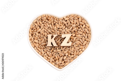 Wheat grains lie in a white plate in the shape of a heart. KZ of wooden letters on the grain. Isolated The concept of import and export, food reserves, the love of bread in Kazakhstan.