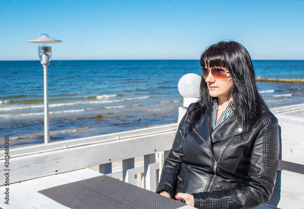 young woman looks at the sea sitting in the outdoor cafe