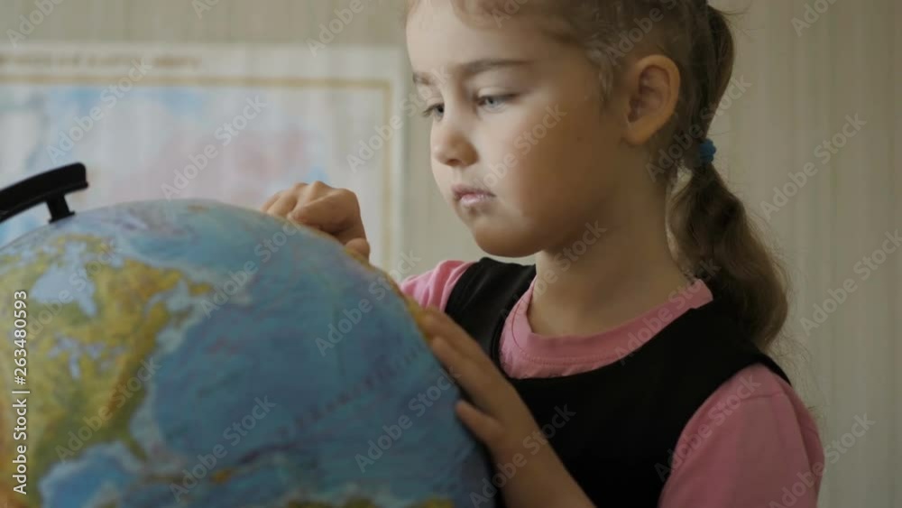 Cute pupil looking at globe in library at the elementary school. Travel planning. Little girl looking at the globe at home in room. Student Child Studying Earth Globe in Library. Closeup. Cute pupil looking at globe in library at the elementary school. Travel planning. Little girl looking at the globe at home in room. Student Child Studying Earth Globe in Library. Closeup.