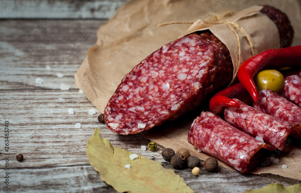 Italian salami with olives and spices on wooden background Italian salami with olives and spices on wooden background