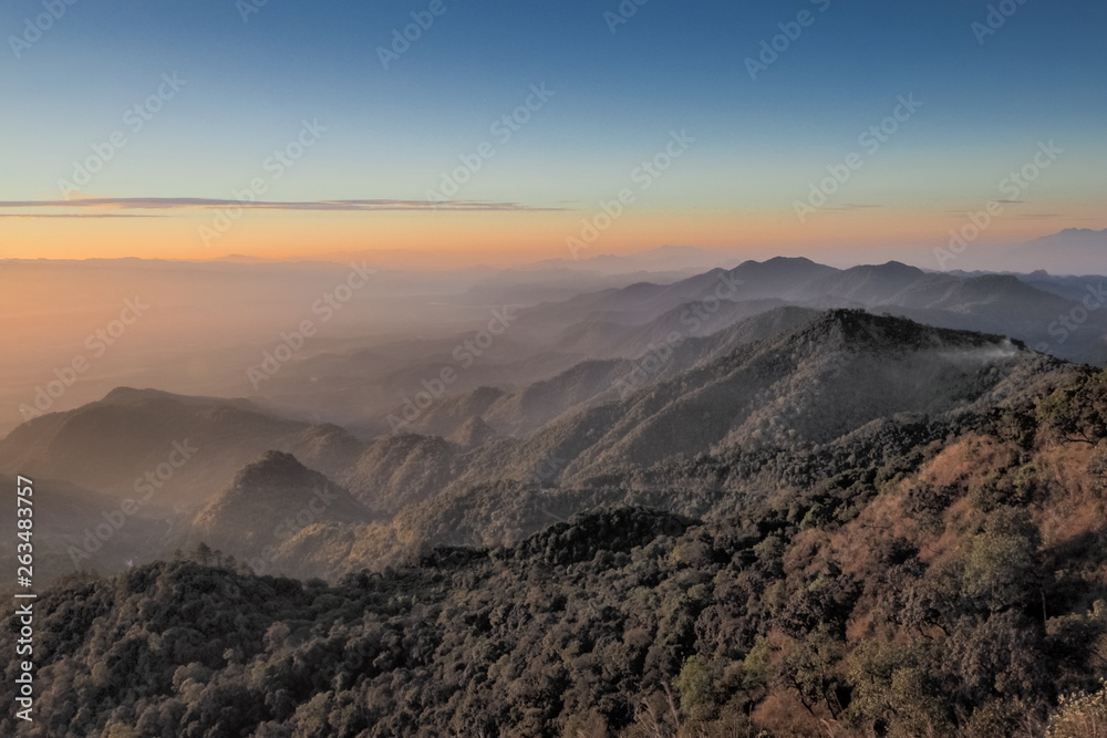 Mountain view misty morning of top hills around with the soft fog with yellow sun light in the sky background, sunrise at top of Doi Ang Khang, Chiang Mai, northern of Thailand.