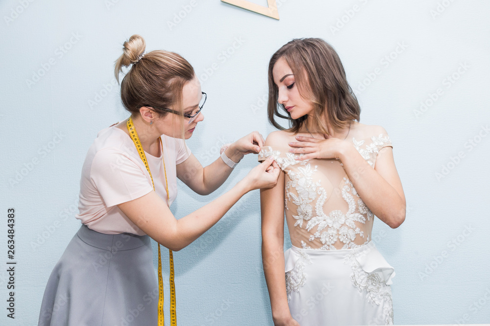 Sewing workshop. Seamstress at work. Seamstress takes measurements of a wedding dress Sewing workshop. Seamstress at work. Seamstress takes measurements of a wedding dress