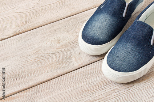 Denim slip-on shoes on wooden background. Top view.