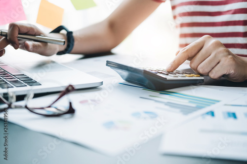 Close up Business woman using calculator and laptop for do math finance on wooden desk in office and business working background, tax, accounting, statistics and analytic research concept