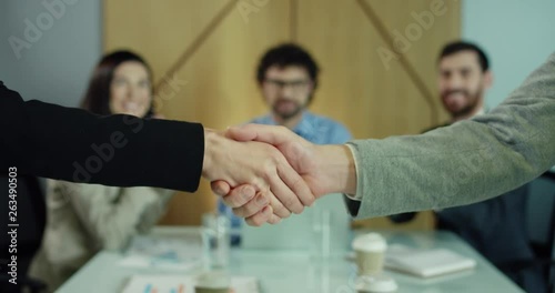 Close up of the Caucasian female and male hands of business people shaking as signing contract or sign of agreement in the office while board of directors applausing on the background. photo