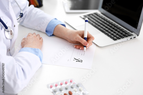 Female doctor filling up prescription form while sitting at the desk in hospital closeup.  Healthcare  insurance and excellent service in medicine concept 
