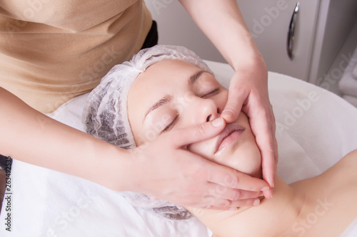 Closeup of young woman receiving face massage from massage therapist.