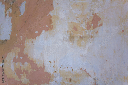 old damaged white gray concrete wall with pink shabby paint, scratches and cracks. rough surface texture