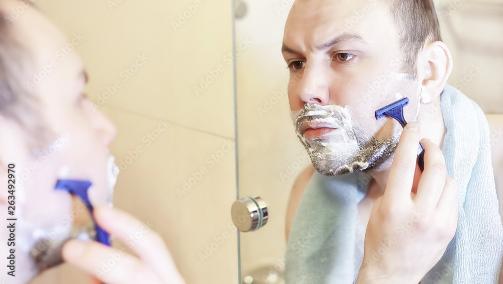 A man shaves in the bathroom in the morning