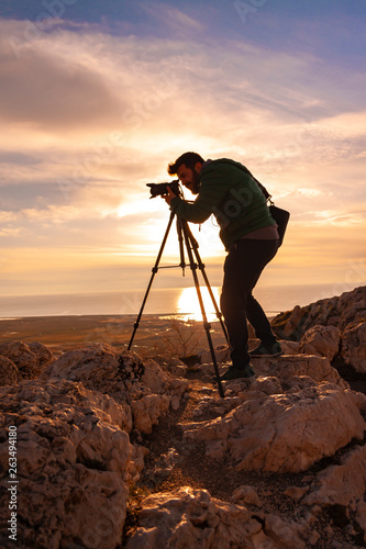 Men photographer on top of mountain at sunset background 