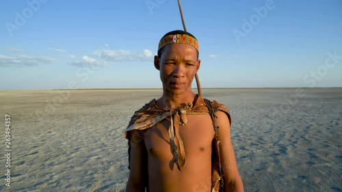 Close-up Portrait of male bushman standing on the Makgadikgadi Pans with blue skies in the background, Botswana photo