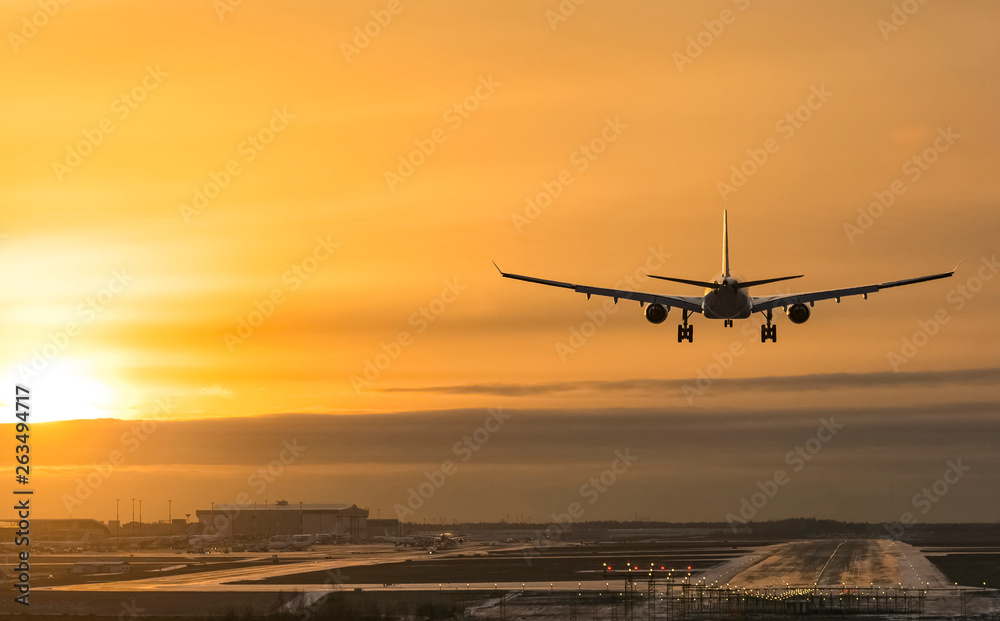 Airplane landing to airport runway in sunset Airplane landing to airport runway in sunset