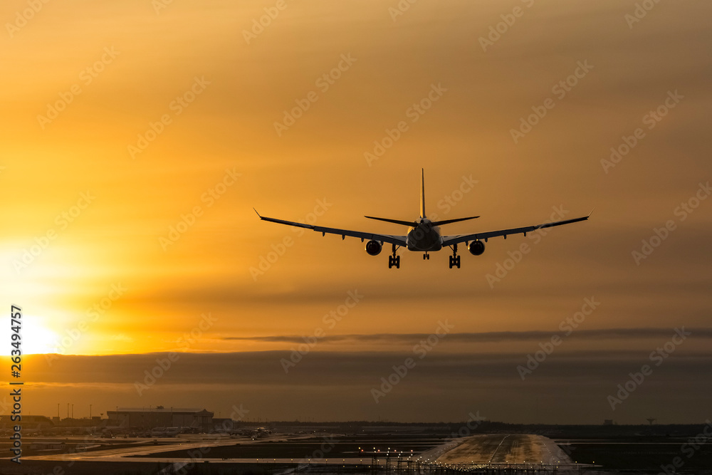 Airplane landing to airport runway in sunset